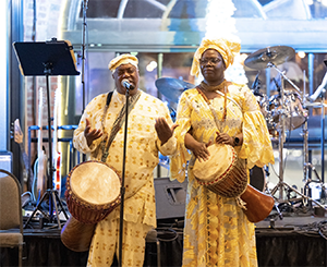 Reggie & Maria Roundtree dressed in Nana attire with drums.
